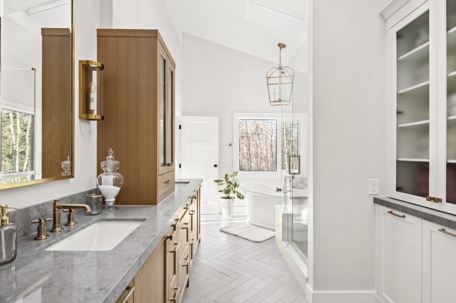 Bathroom with herringbone floors, a wood vanity and marble counters