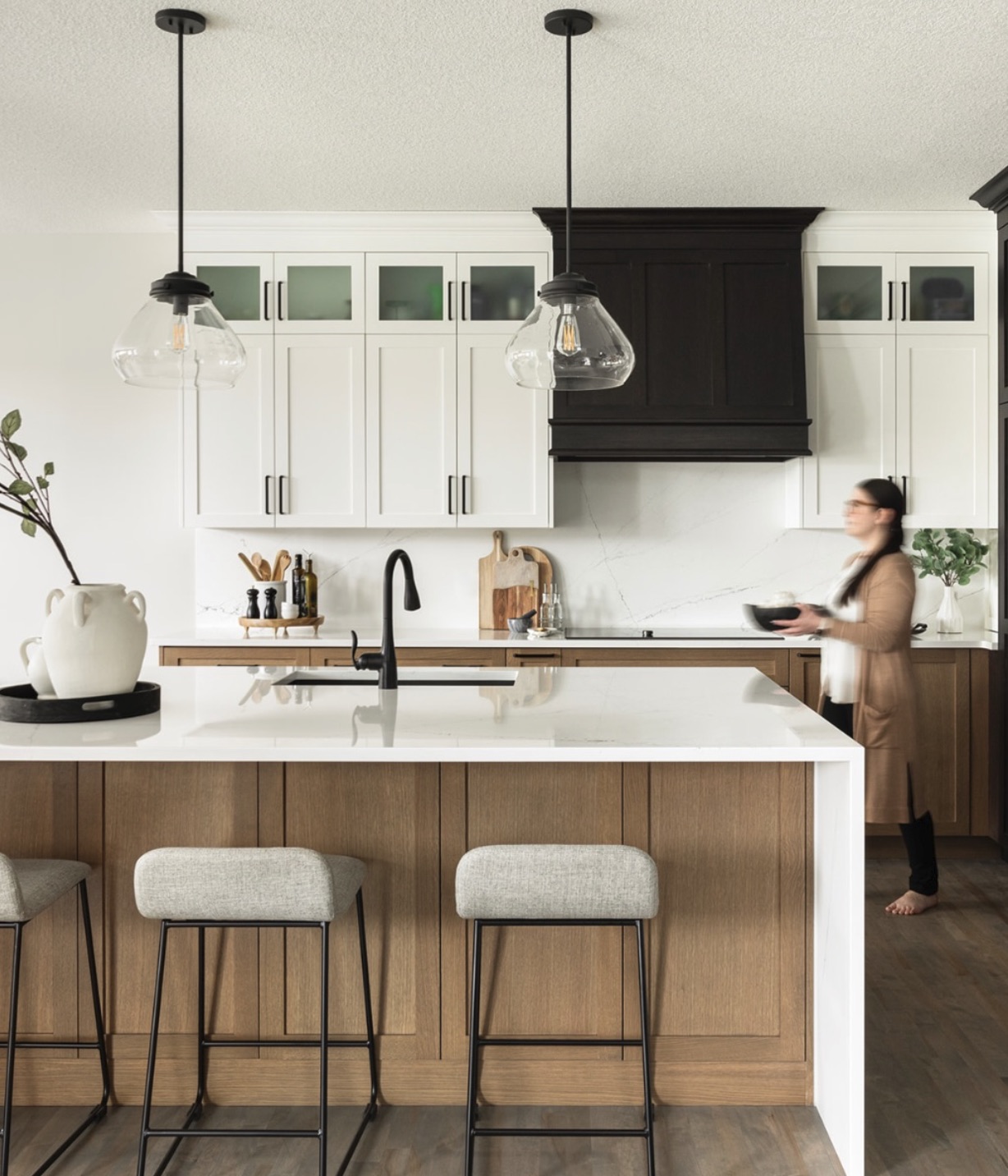 Kitchen with a white oak island, glass pendants and a dark wood hood
